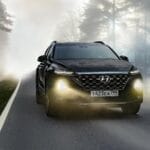 Czarny SUV jedzie we mgle leśną drogą z włączonymi reflektorami