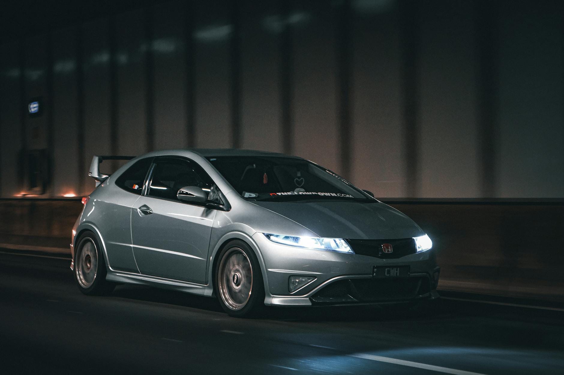 Srebrna Honda jedzie nocą przez słabo oświetlony tunel