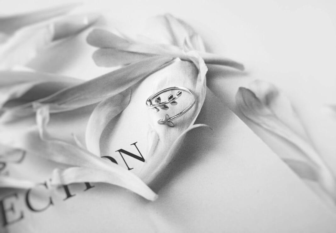 Srebrny pierścionek wśród delikatnych płatków na jednolitym tle