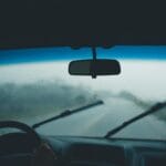 Wnętrze auta w deszczu, widok przez mokrą szybę z pracującymi wycieraczkami