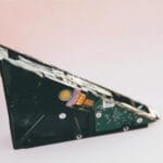 Zbliżenie uszkodzonego dysku twardego z odsłoniętymi częściami na różowym tle