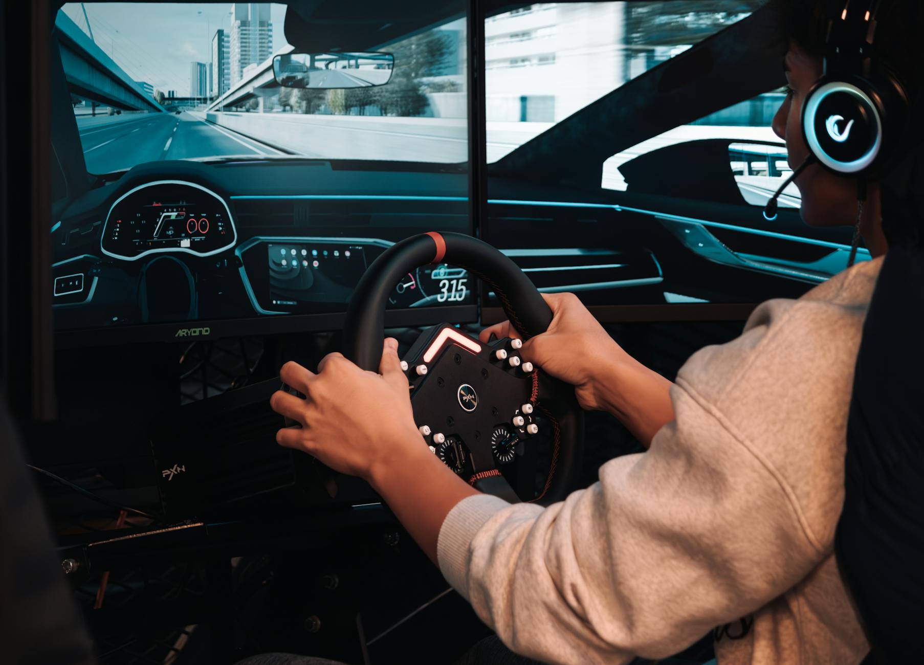 Gracz w realistycznym symulatorze z zaawansowaną kierownicą i ekranami