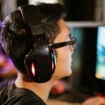 Młody gracz w słuchawkach skupiony na ekranie komputera
