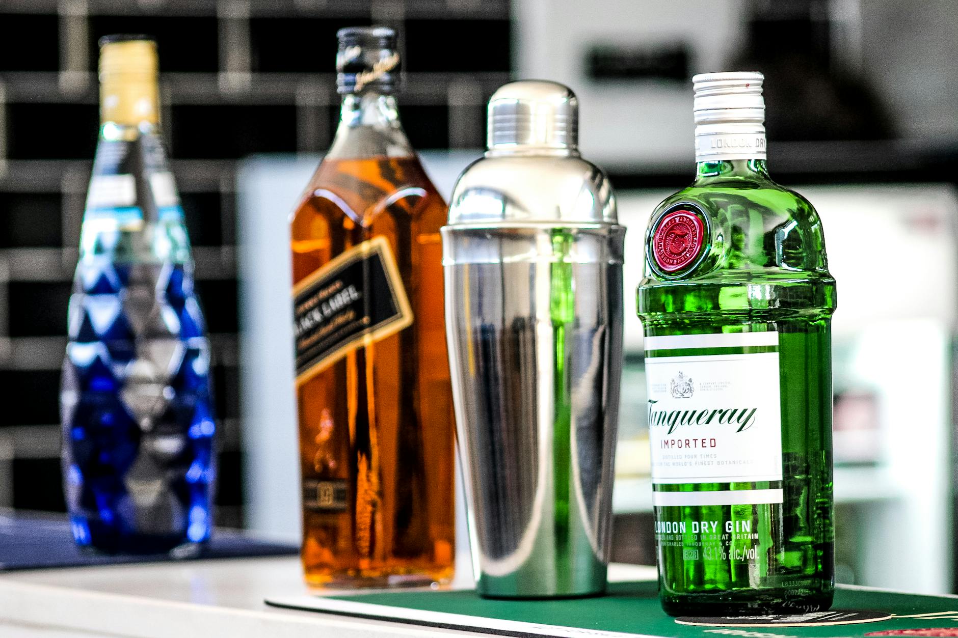 Butelki ginu i innych alkoholi oraz shaker na domowym barku