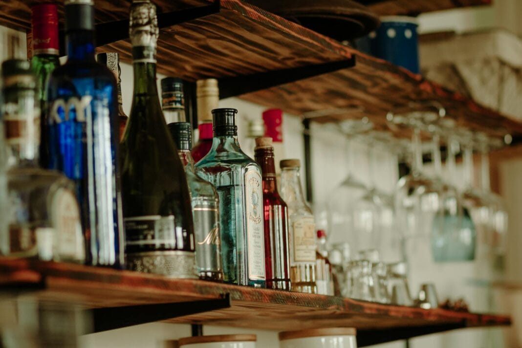 Butelki różnych alkoholi na rustykalnej drewnianej półce barowej