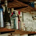 Jak wybrać idealny gin do domowego barku – przewodnik dla początkujących i zaawansowanych Butelki różnych alkoholi na rustykalnej drewnianej półce barowej