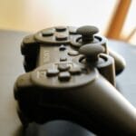 Jak wyciszyć klikające przyciski w joysticku bez utraty gwarancji Czarny bezprzewodowy kontroler do gier leżący na ciemnym biurku