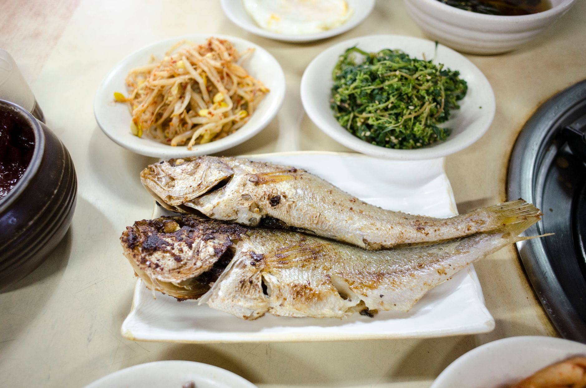 Grillowana ryba z koreańskimi przystawkami z warzyw na talerzu