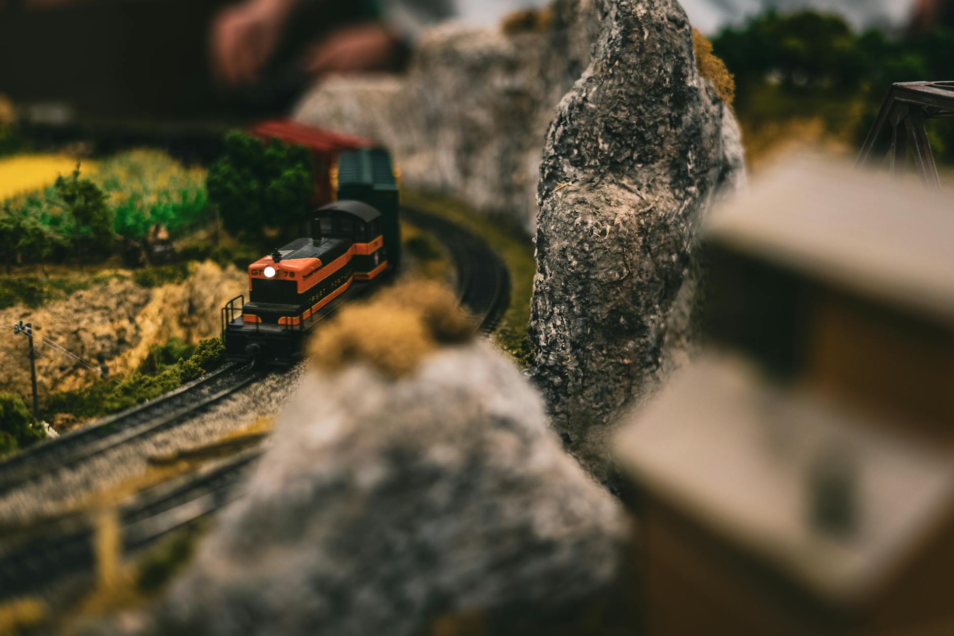 Miniaturowy pociąg jedzie przez realistyczną makietę kolejową