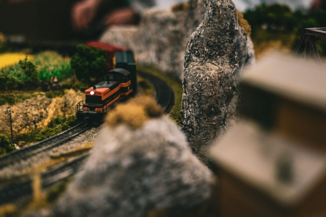 Miniaturowy pociąg jedzie przez realistyczną makietę kolejową
