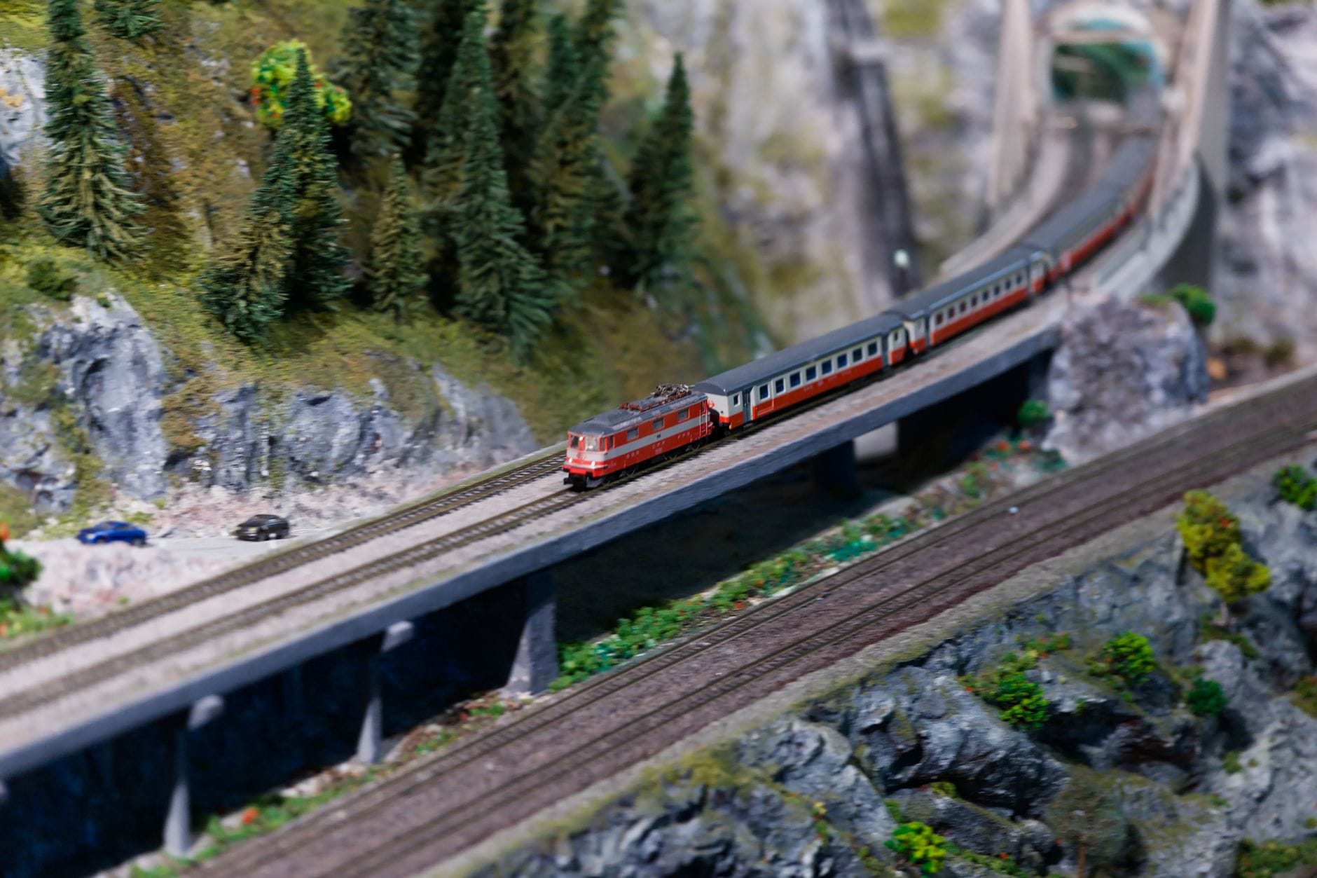 Modelowy pociąg na moście w miniaturowym górskim krajobrazie